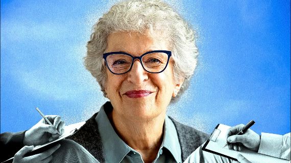 Close-up portrait of an older woman with short grey hair and blue-framed glasses against a blue background, with monochrome hands on either side holding pens and clipboards